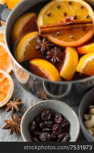 christmas and seasonal drinks concept - pot with hot mulled wine, orange slices and aromatic spices on grey background. pot with hot mulled wine, orange slices and spices