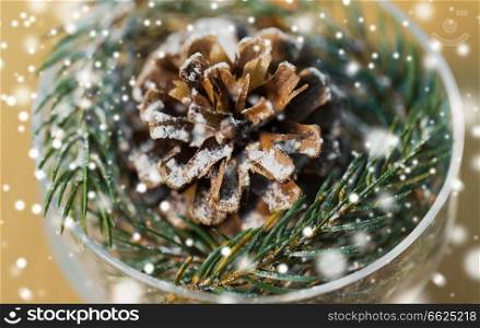 christmas and winter concept - close up of decoration of fir twig with pinecone in dessert bowl over snow. close up of christmas decoration of fir and cone