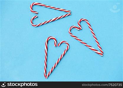 christmas and winter holidays concept - candy cane decorations in shape of hearts on blue background. candy cane decorations in shape of hearts