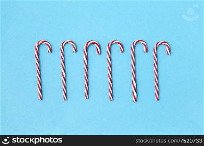 christmas and winter holidays concept - candy cane decorations on blue background. candy cane decorations on blue background
