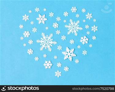 christmas and winter holidays concept - white snowflake decorations in shape of heart on blue background. snowflake decorations in shape of heart