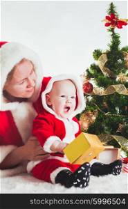 Christmas baby and mom under the fir tree isolated. Christmas baby and mom