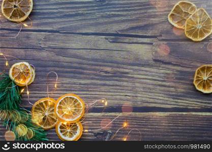 Christmas background from dried oranges, pine twig and garland on a wooden table. Top view. Copyspace. Christmas background from dried oranges, pine twig and garland on a wooden table