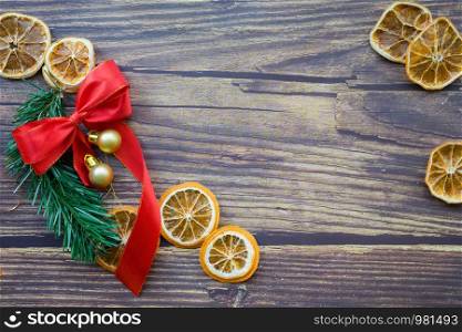 Christmas background from dried oranges, pine twig and red bow on a wooden table. Top view. Copyspace.. Christmas background from dried oranges, pine twig and red bow on a wooden table