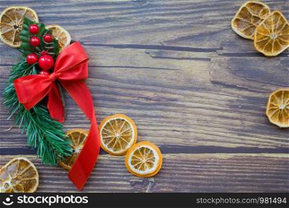 Christmas background from dried oranges, pine twig and red bow on a wooden table. Top view. Copyspace. Flatlay. Christmas background from dried oranges, pine twig and red bow on a wooden table