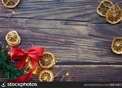Christmas background from dried oranges, pine twig, red bow and garland on a wooden table. Top view. Copyspace. Christmas background from dried oranges, pine twig, red bow and garland on a wooden table