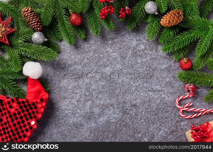 Christmas background. Top view border green pine cones fir tree branches with Xmas decoration and Santa hat on concrete table background with copy space for text, Happy new year day concept
