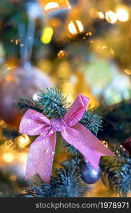 Christmas background with beautiful pink bow on green branch of decorated Christmas tree and bokeh lights background, copy space, Holiday,xmas concept space for text. Christmas background with beautiful pink bow on green branch of decorated Christmas tree and bokeh lights background, copy space, Holiday,xmas concept