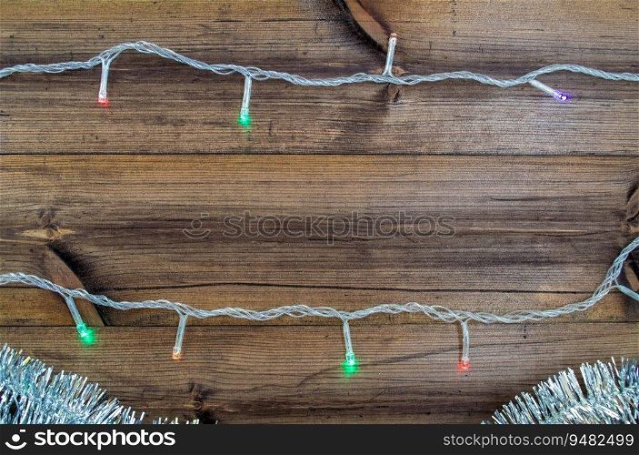 Christmas background with copy space in the center. Silver tinsel and garland on a wooden background. Festive background.
