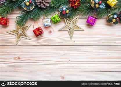 Christmas background with decoration, gift box, Star shape, Bell and pine tree branches on wooden board, Happy New Year and Xmas Holidays banner. Top view and Copy Space for your text