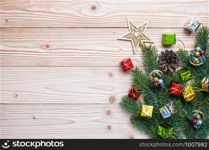 Christmas background with decoration, gift box, Star shape, Bell and pine tree branches on wooden board, Happy New Year and Xmas Holidays banner. Top view and Copy Space for your text