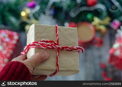 Christmas background with decorations and gift boxes on blurred background. The woman is holding gift package in hand