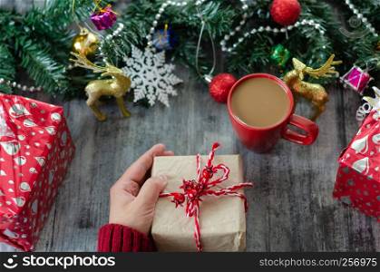 Christmas background with decorations and gift boxes on wooden board.The woman is holding gift package in hand