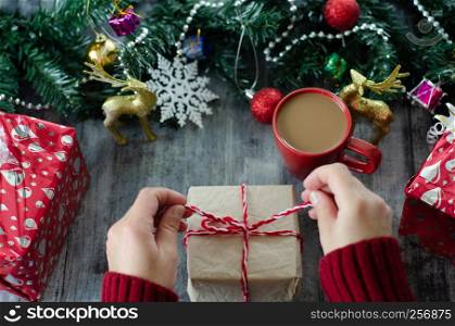 Christmas background with decorations and gift boxes on wooden board.The woman is unpacking gift.