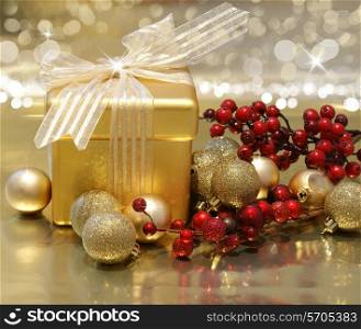 Christmas background with gift box, berries and baubles on gold background