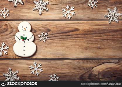 Christmas background with gingerbread cookie in shape of snowman on wooden table. Copy space. Top view