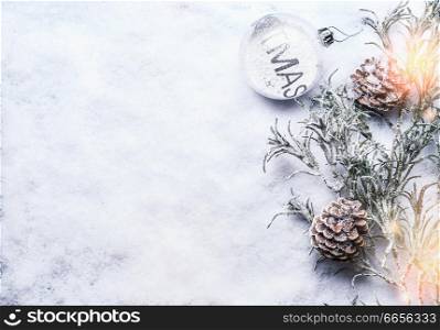 Christmas background with glass bauble , frozen branches and cones on snow with snowfall and bokeh, top view with copy space for your design, frame