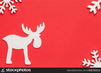 Christmas background with moose and snowflakes on red paper. Top view