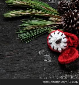 Christmas background with pine cone, green leaf and red clock on black wooden background