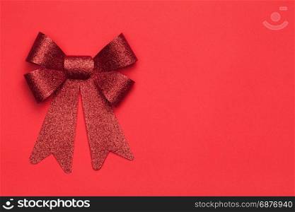 Christmas background with red bow on red paper background. Copy space. Top view
