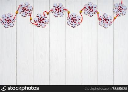 Christmas background with red felt snowflakes garland on white wooden background. Top view, flat lay with copy space, banner, header, New Year background. Christmas background with red felt snowflakes garland. Top view, flat lay with copy space