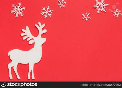 Christmas background with reindeer and snowflakes on red paper. Top view