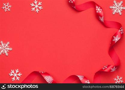 Christmas background with snowflakes and ribbon on red paper. Copy space. Top view