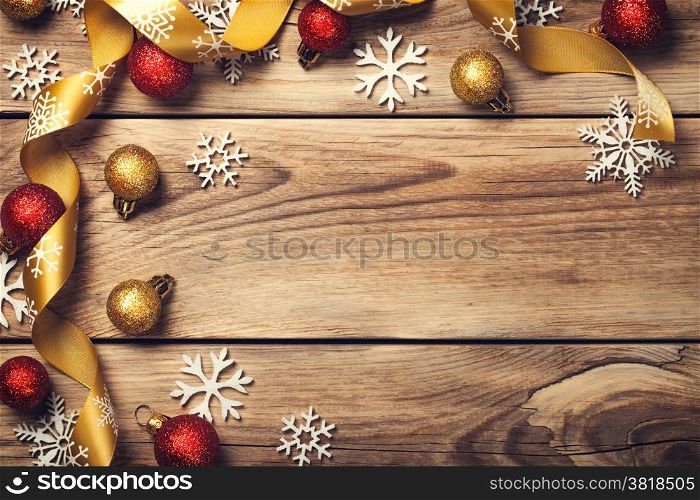 Christmas background with snowflakes, red and gold balls on wooden table. Copy space. Top view