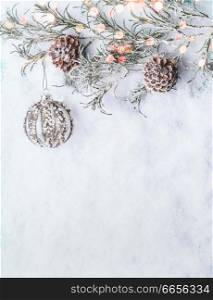 Christmas background with vintage bauble , frozen branches and cones on snow with bokeh, top view with copy space for your design, border