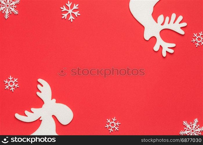Christmas background with white snowflakes, reindeer and moose on red paper. Top view