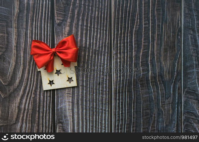 Christmas background with wooden decorative gift and red bow on the old wooden board Copy space. Christmas background with wooden decorative gift and red bow on the old wooden board