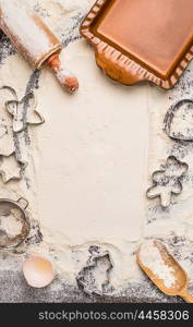 Christmas baking background with flour, rolling pin, cookie cutter and rustic bake pan, top view, place for text. Vertical.
