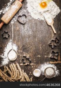 Christmas baking background with ingredients and tools: Cookie Cutters, Cups, Mats, Rolling Pin, spoon . Dark, rustic, top view, frame