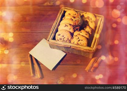christmas, baking, culinary, holidays and food concept - close up of oat cookies in wooden box with blank greeting card and cinnamon on table