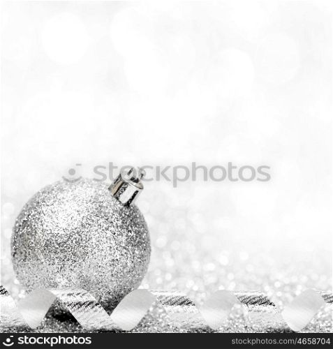 Christmas ball and curly decorative ribbon on bokeh background