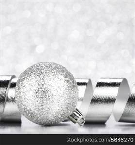 Christmas ball and curly decorative ribbon on bokeh background