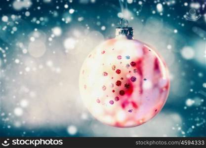 Christmas ball, hanging at blue bokeh background with snow