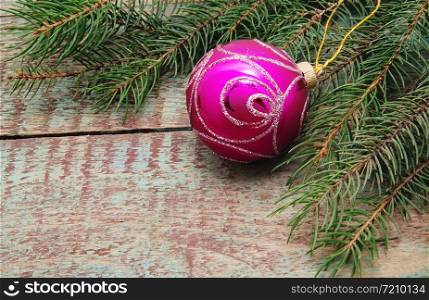 Christmas ball on wooden background with branches of green spruce.