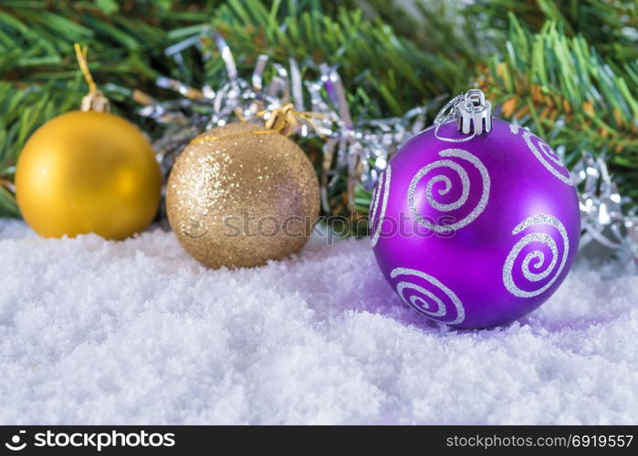 Christmas balls on snow. Background of Christmas tree branches and tinsel. With congratulatory text