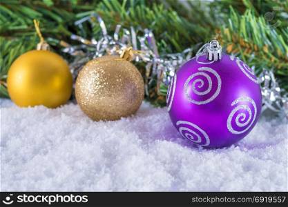 Christmas balls on snow. Background of Christmas tree branches and tinsel. With congratulatory text