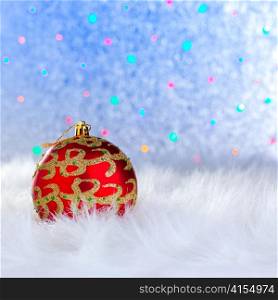 christmas bauble on white fur and colorful lights