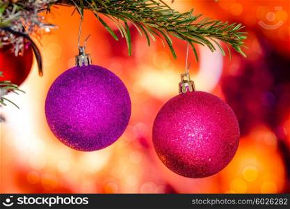 Christmas baubles in violet colors hanging from a branch