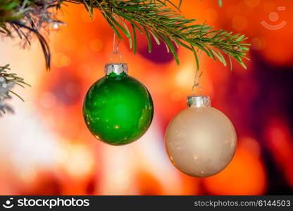 Christmas baubles on a pine branch by a fireplace