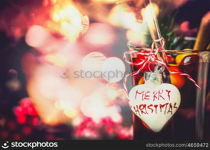 Christmas bokeh background with glass of mulled wine or punch with heart and inscription Merry Christmas, close up