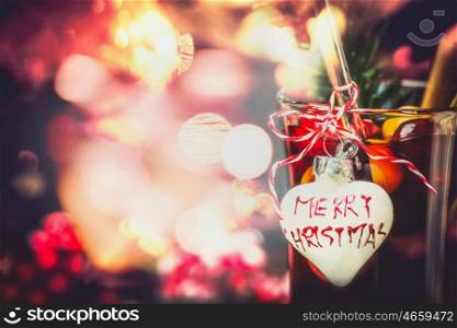 Christmas bokeh background with glass of mulled wine or punch with heart and inscription Merry Christmas, close up