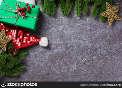 Christmas border decorations holiday, Top view from above green fir tree branches with Xmas ornament baubles, the star, gift box and Santa hat on table concrete background, Happy new year concept