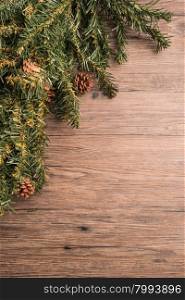 Christmas border design with pine cone and fir branches over old oak wood
