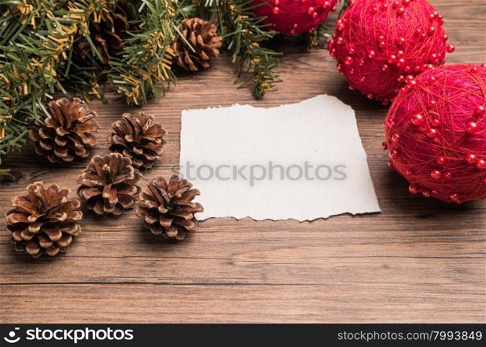 Christmas border design with pine cone, fir branches and christmas balls on parchment paper over old oak wood