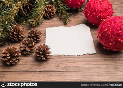Christmas border design with pine cone, fir branches and christmas balls on parchment paper over old oak wood
