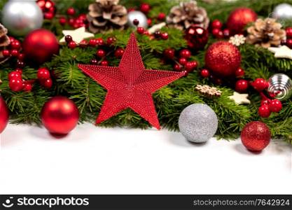 Christmas Border frame of tree branches on white background with copy space isolated, red and silver decor, berries, stars, cones. Christmas frame of tree branches